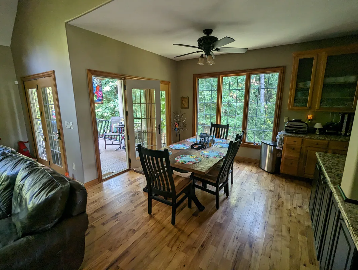 Columbus dining area before 2 story addition. Features wood floor, large windows, deck view, oak cabinets, and ceiling fan.