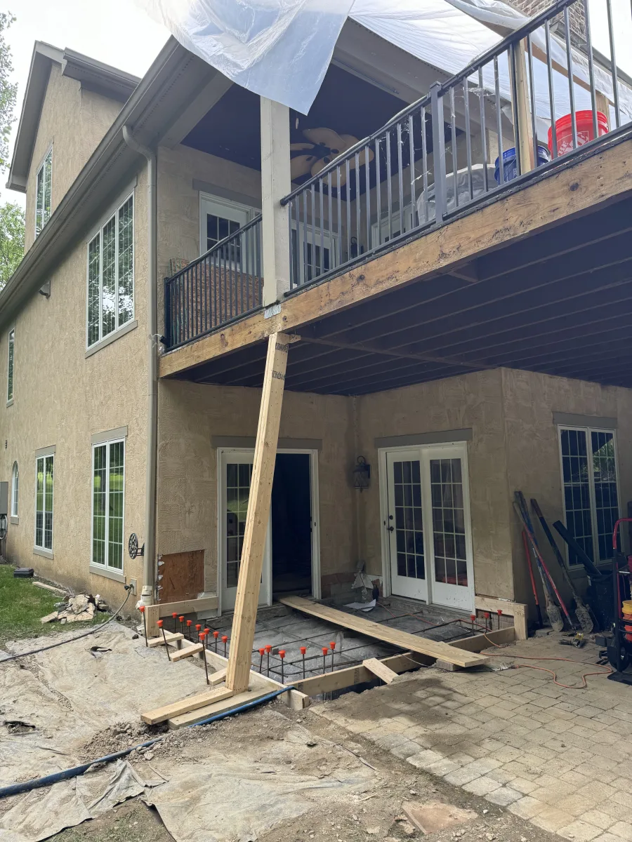 Columbus 2 story addition in progress: new concrete foundation with rebar, temporary deck support, beige stucco home exterior.