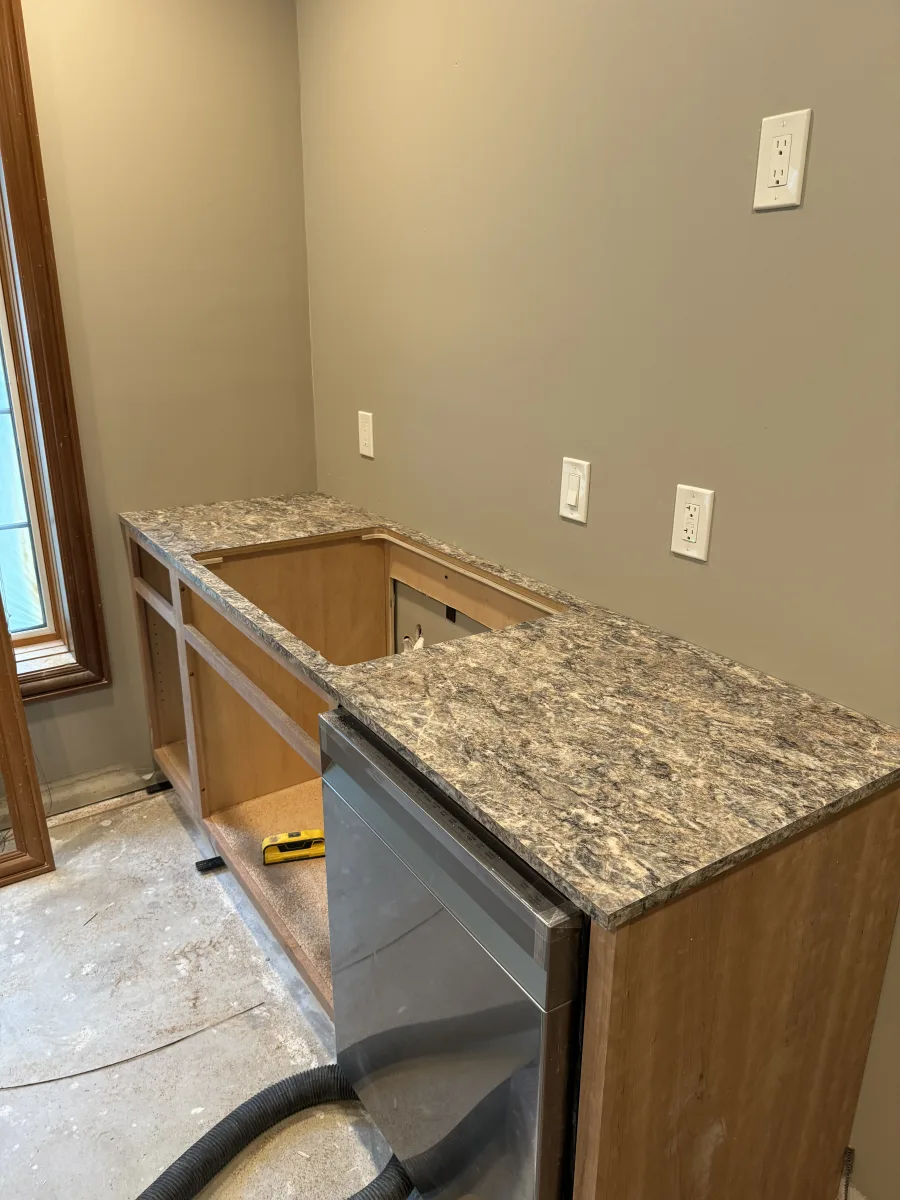 Columbus kitchen remodeling: In-progress custom wood cabinets, speckled laminate countertop, and dishwasher installation.
