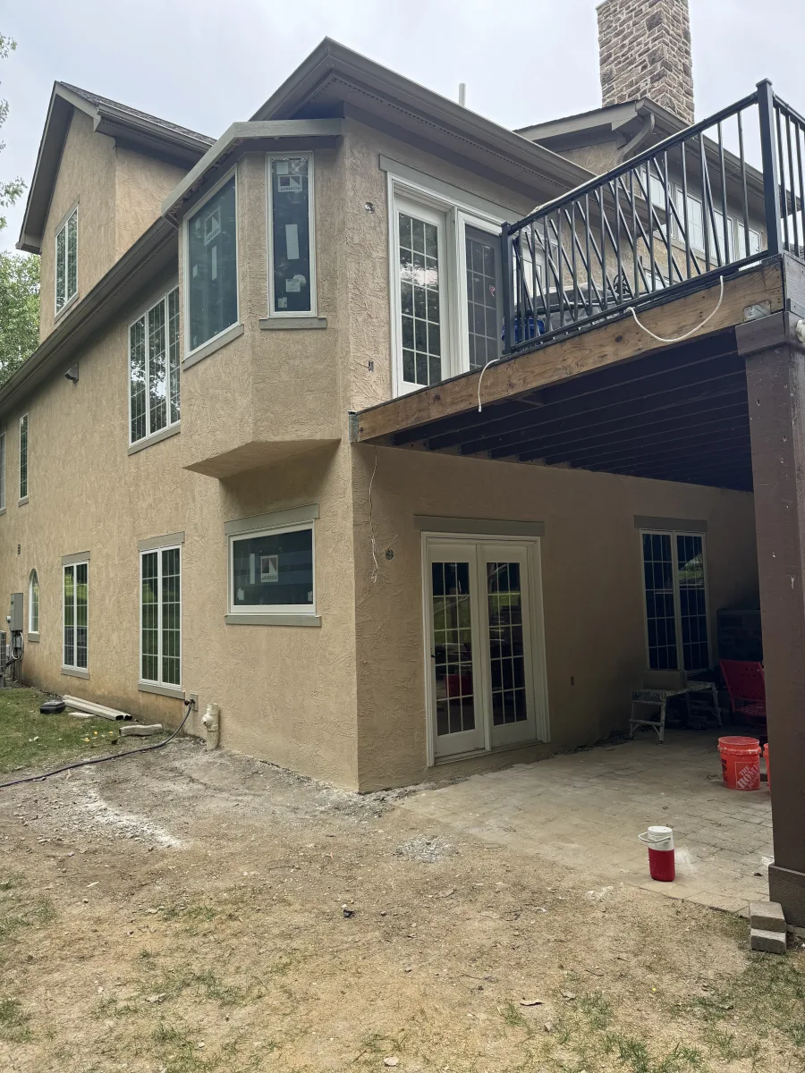 Columbus 2-story addition exterior after: tan stucco, new white Andersen windows, upper deck with black railing, lower patio.