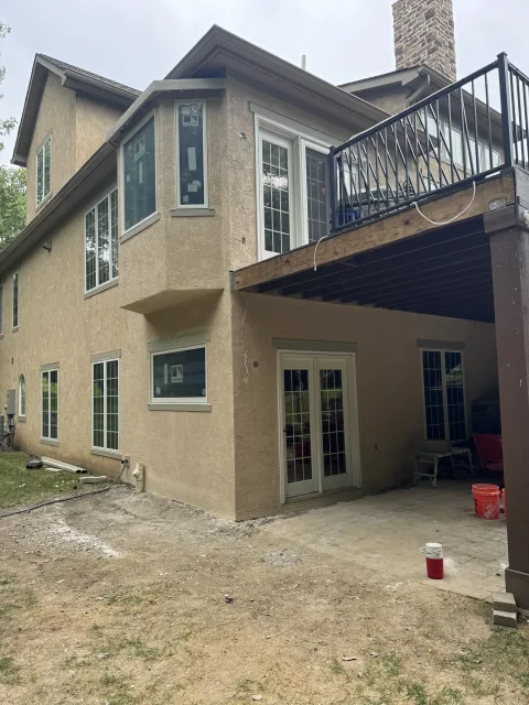 Columbus 2-story addition exterior after: tan stucco, new white Andersen windows, upper deck with black railing, lower patio.