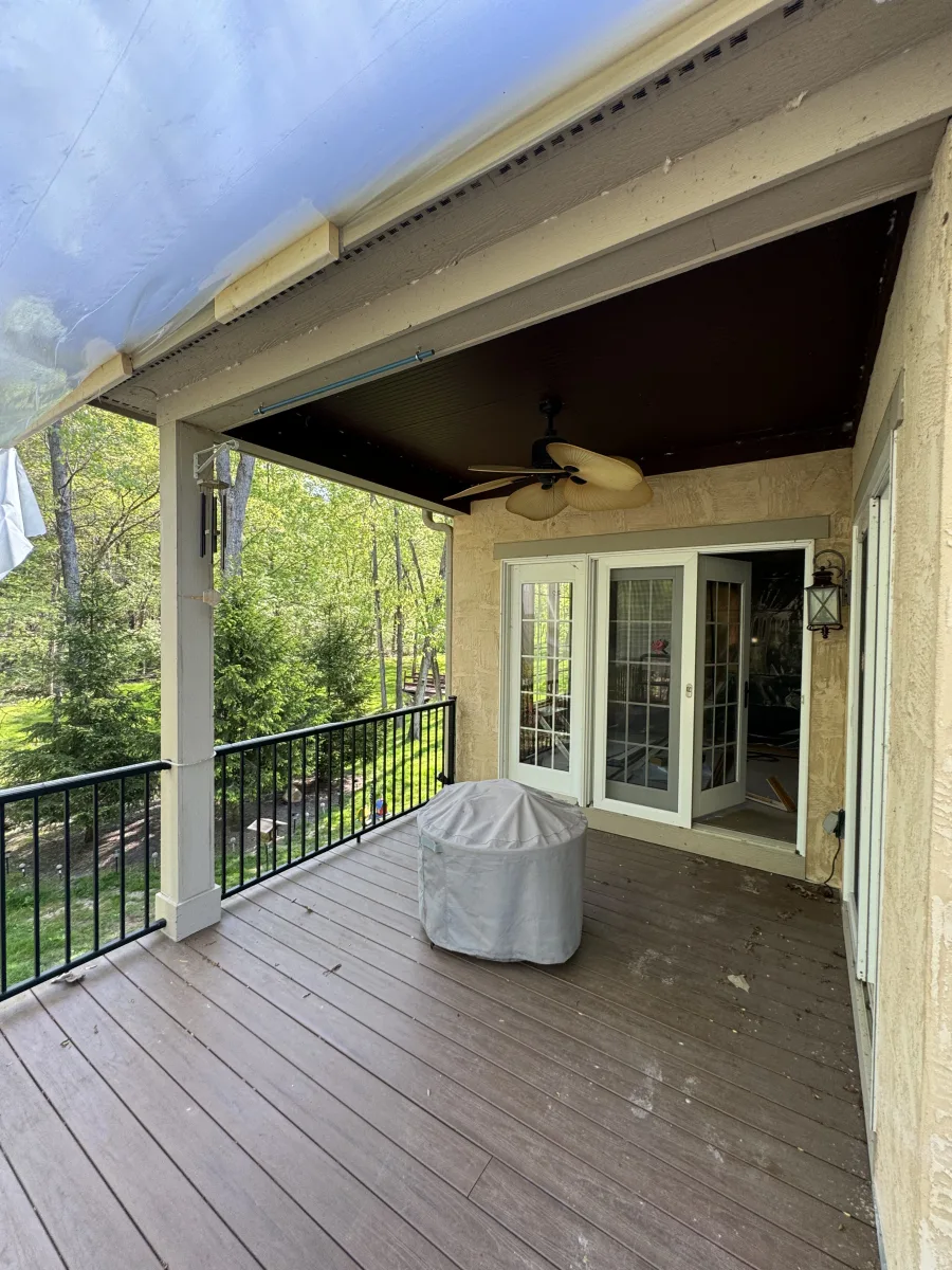 Columbus OH 2 Story Addition before: Covered deck with worn composite boards, stucco wall, ceiling fan, and plastic tarp.