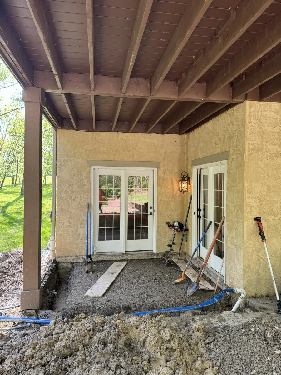 Columbus 2 Story Addition in-progress exterior. Foundation excavation, utility pipes, stucco wall, and deck structure.
