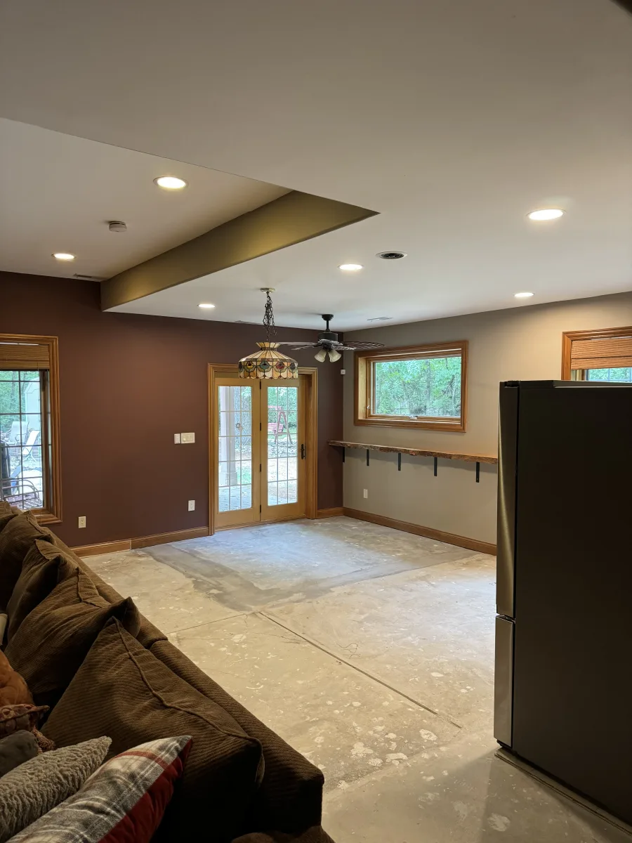 Columbus 2 Story Addition interior in progress: concrete floor, brown walls, wood doors, recessed lighting, and shelf.
