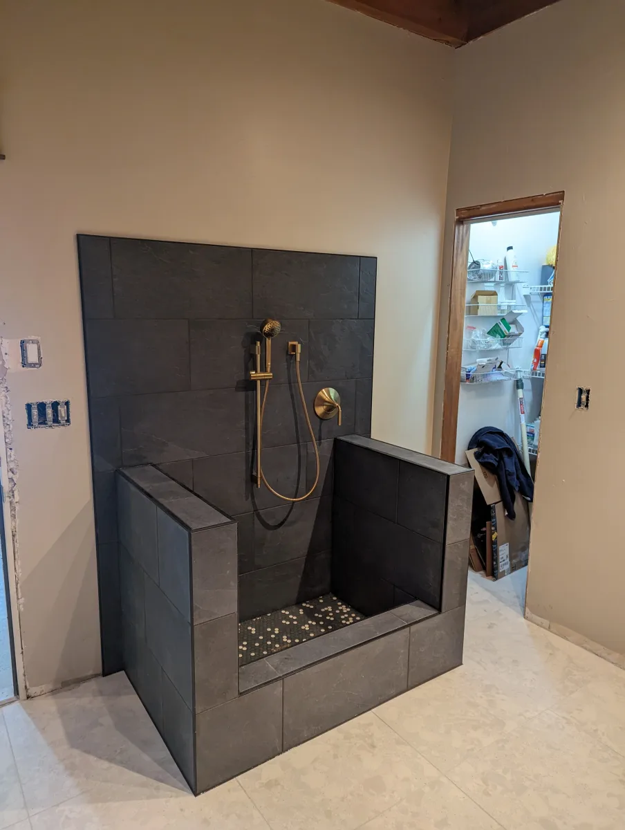 Columbus custom entryway dog bath with dark gray tiles, gold shower fixtures, and mosaic floor. 614 Remodeling Pros bathroom remodel.