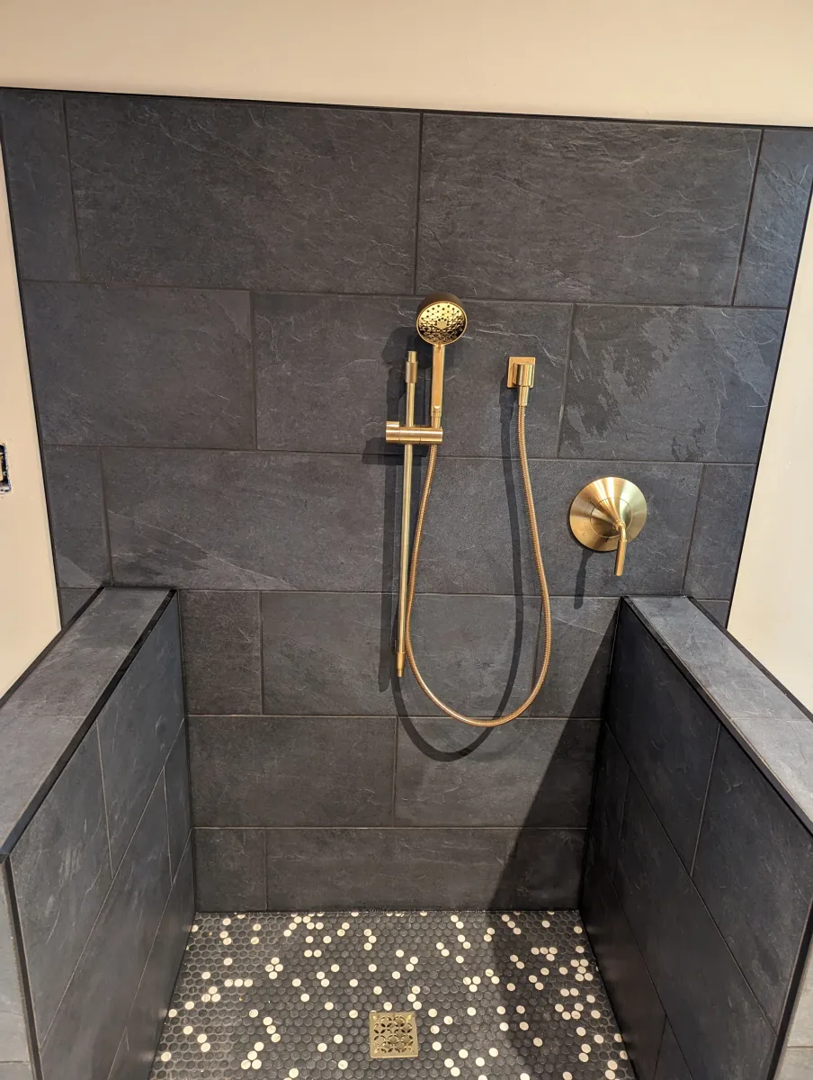 Columbus dog bathing station with dark gray slate tiles, brass shower fixtures, and mosaic penny tile floor. Bathroom remodel.