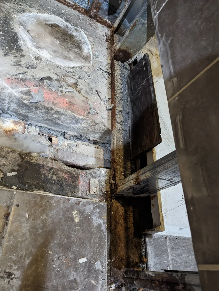 Before extensive commercial shower renovation in Columbus: rusted metal structure, damaged concrete, and exposed subfloor.