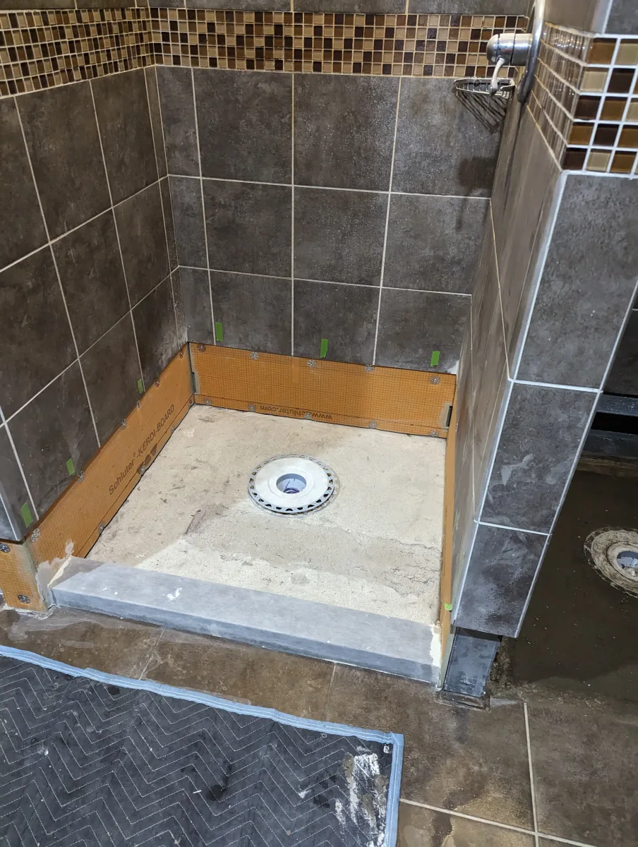 Columbus commercial bathroom remodeling, showing Kerdi-Board, new drain, and dark tile installation.