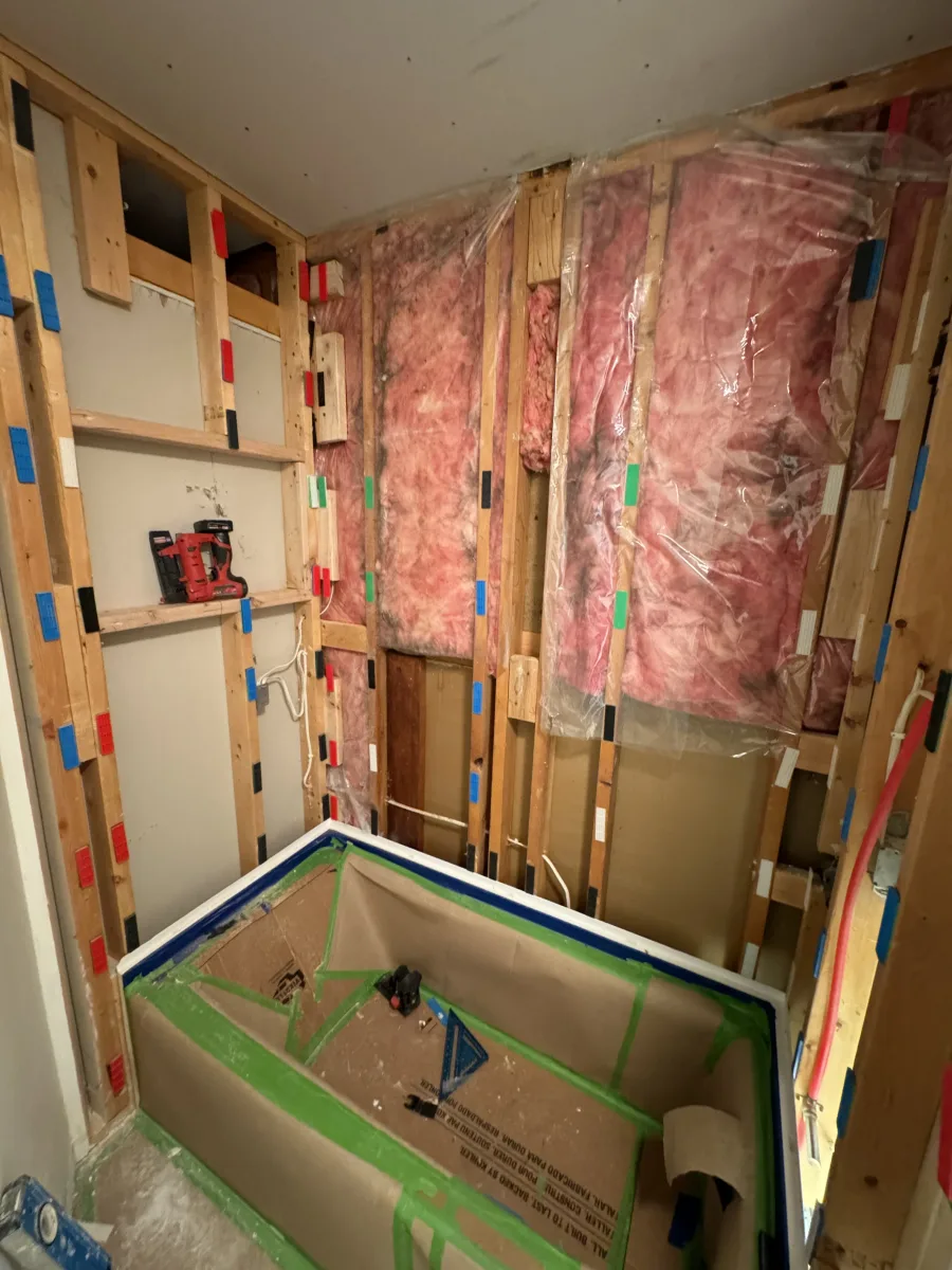 Columbus bathroom remodel progress: wall framing, insulation, and protected bathtub for guest bath renovation.