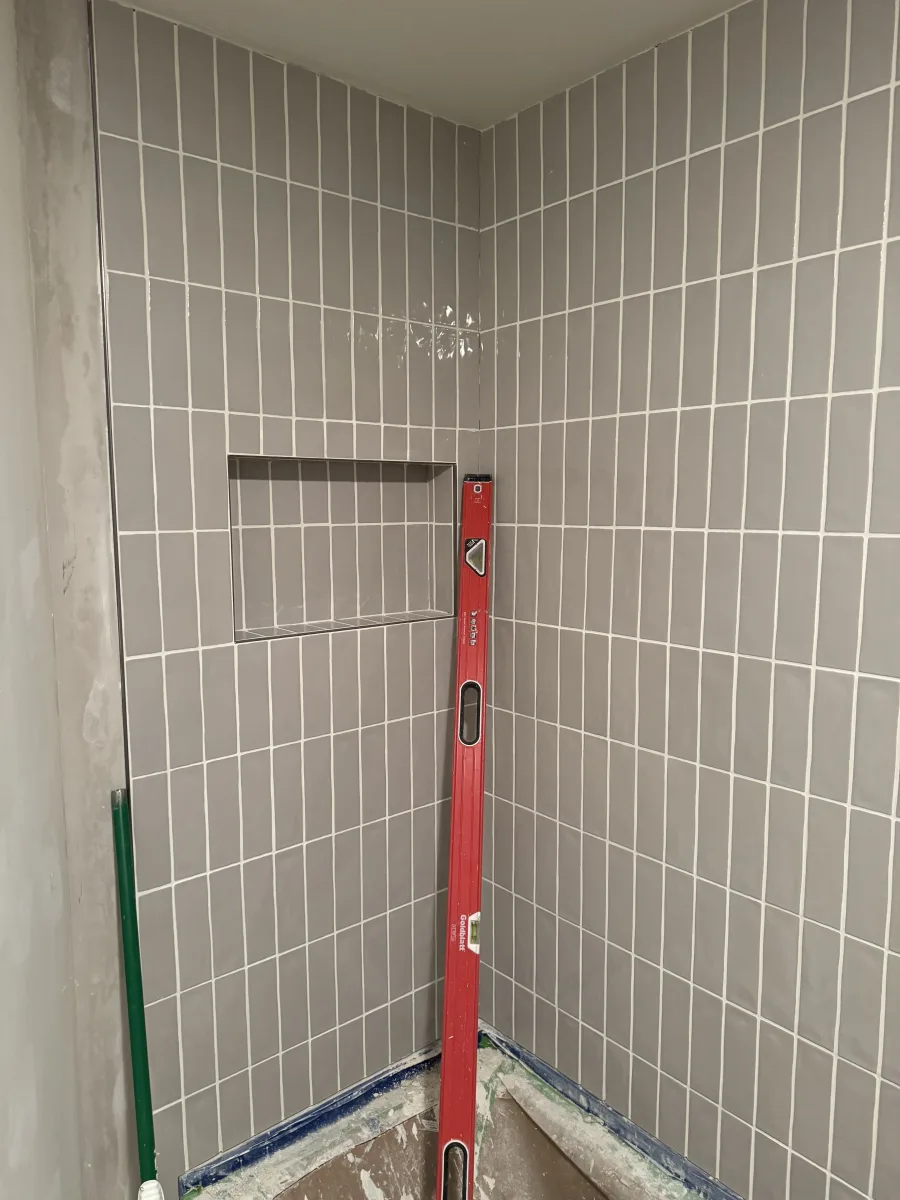 Columbus bathroom remodeling: Modern grey vertical subway tile shower walls with a recessed niche and white grout lines.