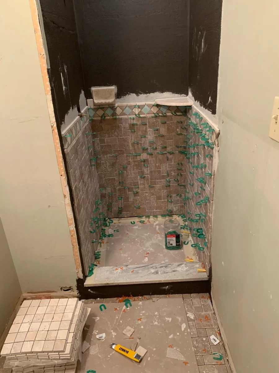 Columbus master bathroom shower remodel with brown and teal wall tile installation, floor tile prep, and visible tile spacers by 614 Remodeling Pros.