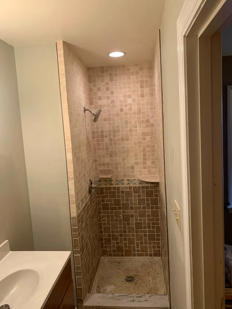 Columbus master bathroom shower tile renovation featuring beige & brown mosaic tiles, accent border, & corner bench.