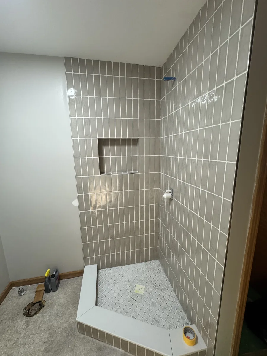 Columbus modern bathroom remodel featuring new gray vertical subway shower tiles, mosaic floor, and custom niche.