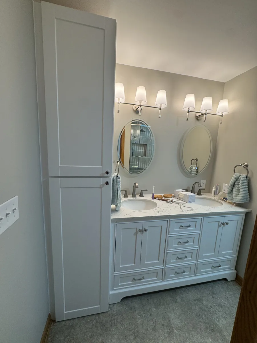 Columbus modern bathroom remodel featuring white dual vanity, quartz counter, tall linen cabinet, illuminated mirrors, and stylish lighting.