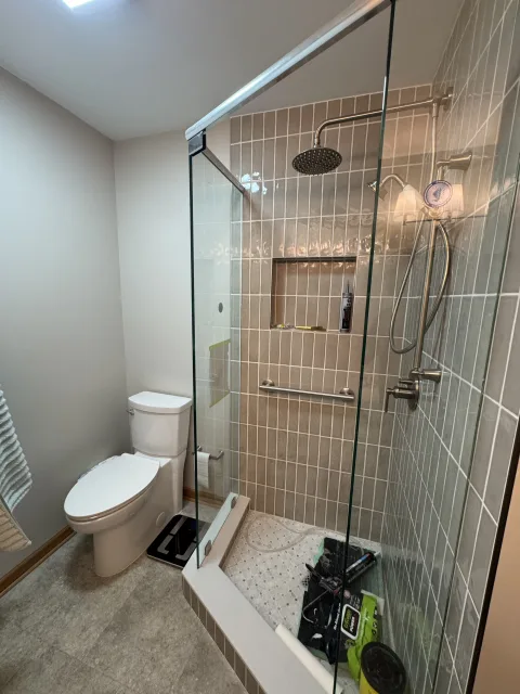 Modern Columbus bathroom remodeling with glass shower enclosure, gray subway tiles, rain head, and white toilet by 614 Property Maintenance.