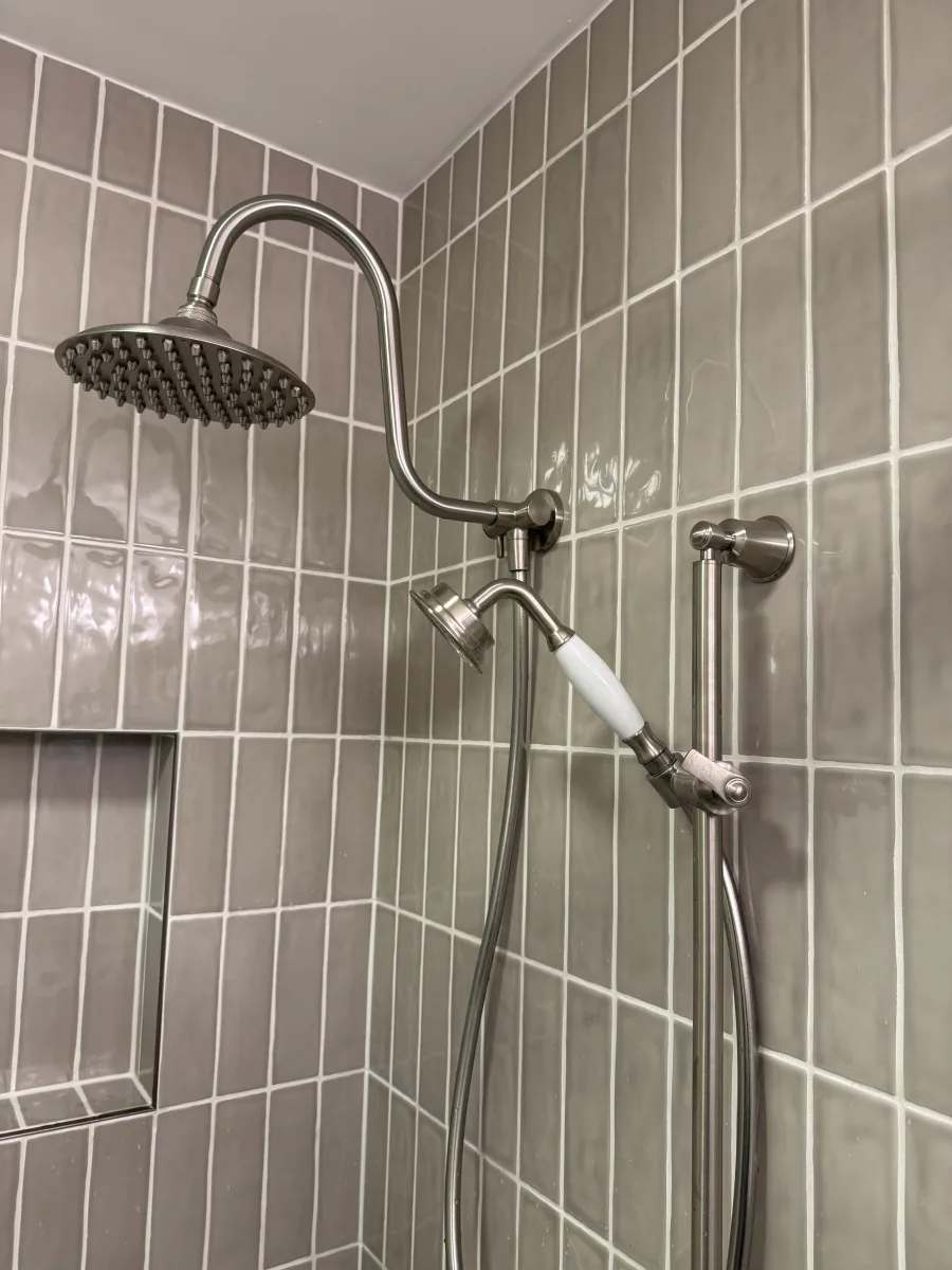 Columbus bathroom remodel featuring brushed nickel rain and handheld shower with gray subway tiles and niche by 614 Remodeling Pros.