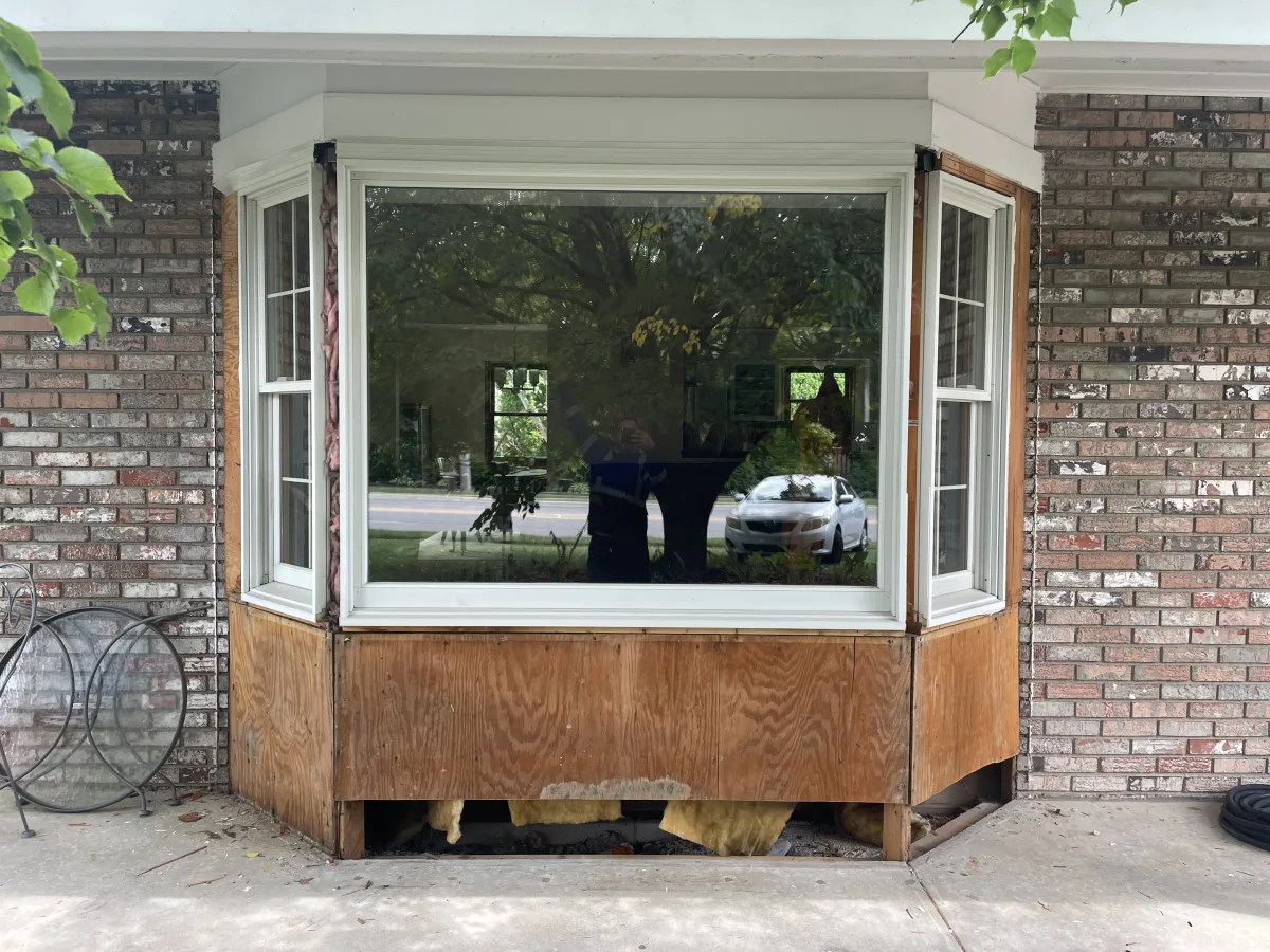 Columbus exterior home remodeling: New white bay window installed, showing plywood and insulation during transformation.